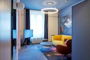 a living room with a yellow couch and a tv at BOUTIQUE Hotel by Continental Park in Lucerne