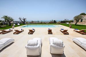 a pool with white chairs and a swimming pool at Poggio Leano Boutique Hotel in Donnalucata