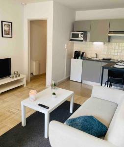 salon z białą kanapą i stołem w obiekcie KASA VOYTIER Parking privé & Wifi - Balcon & Ascenseur w mieście Saint Etienne
