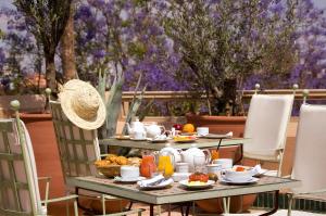 ein Tisch mit Frühstücksspeise darauf mit Bäumen im Hintergrund in der Unterkunft Les Jardins De La Médina in Marrakesch