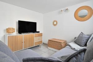 een woonkamer met een bank en een tv op een kast bij Jolie appartement climatisé in La Ciotat