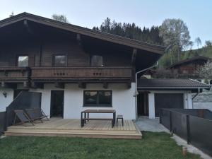 una casa con una terraza con un banco. en Alpen Chalet Bramberg, en Bramberg am Wildkogel