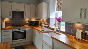 a kitchen with white cabinets and wooden counter tops at deesideholidaycottages in Dinnet