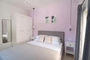 a white bedroom with a bed with two pillows at Antheon apartments in Vathi