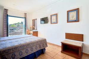 a bedroom with a bed, desk, and window at Hotel Villa Frigiliana in Frigiliana