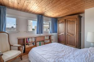 Un dormitorio con una cama y una silla y ventanas. en Superbe vue Mer - Vacances à 5 personnes à Arzon, en Arzon