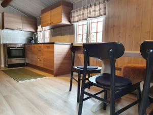 a kitchen with wooden cabinets and a black chair at Groven Camping & Hyttegrend in Åmot