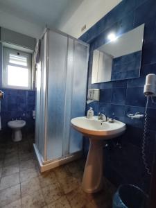 ein blau gefliestes Badezimmer mit Waschbecken und Dusche in der Unterkunft Hotel Il Dollaro in Villa San Giovanni + 9 Fotos