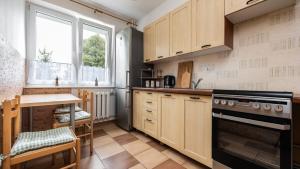 a kitchen with wooden cabinets and a table and a stove at Apartament - 3min od plaży - Chillout vibes in Gdańsk