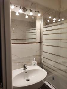 La salle de bains blanche est pourvue d'un lavabo et d'une douche. dans l'établissement Apartmán Masarykova třída 61, à Olomouc