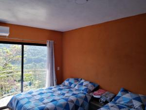 - une chambre avec un lit et une grande fenêtre dans l'établissement Hotel El Mirador, à Xilitla