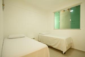 ein weißes Zimmer mit zwei Betten und einem Fenster in der Unterkunft Venha curtir essa maravilha! Frente para o mar! in Angra dos Reis