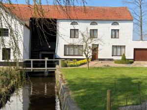 a white house with a bridge next to a river at Vakantiewoning Wurfeldermolen in Maaseik