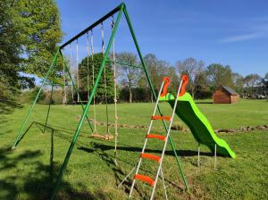 une aire de jeux vide avec toboggan et balançoires dans l'établissement Chalets "Ô Cœur des Puys", à Ceyssat