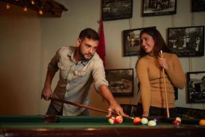 a man and a woman standing next to a pool table at Hortensias Chalets Vara blanca in Heredia