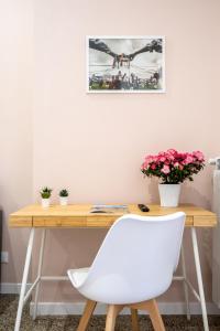Via Venezia 32 Room في بتراليا سوتانا: طاولة خشبية مع كرسي أبيض وورود