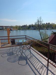 a table and chairs sitting on a patio next to a river at Apartament nad Jeziorakiem in Iława