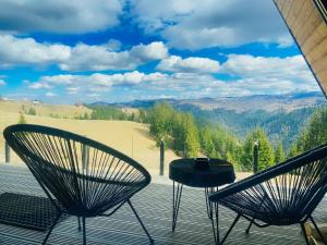 two chairs and a table on a deck with a view at Nordik Cabin - Aframe with 2 bedrooms in Mărişel