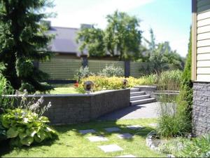 a garden with a stone retaining wall and flowers at Tammehouse in Otepää