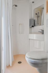 a white bathroom with a toilet and a sink at Premiere Classe Rouen Nord - Barentin in Barentin