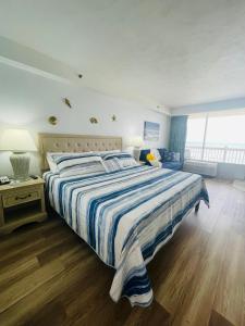 um quarto com uma cama grande e um edredão listrado em Daytona Beach Resort Oceanfront CondoStudio em Daytona Beach
