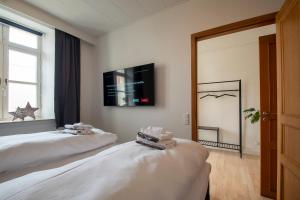 two beds in a room with a tv on the wall at Central City Apartment in Sønderborg