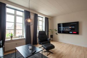 a living room with a chair and a tv at Central City Apartment in Sønderborg