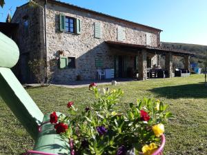 a stone house with flowers in front of it at Podere Oliveta in Montecatini Val di Cecina