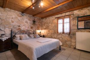 a bedroom with a bed and a stone wall at Gerakopetra in Vasilikos