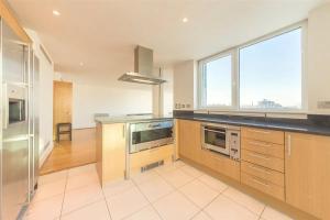 a kitchen with stainless steel appliances and a large window at Panoramic Riverside Facing - 2 Bed - 2 Bath - 2 Balconies - London Nine Elms in London +8 photos
