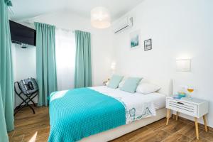 a white bedroom with a bed and green curtains at Jele Rooms in Dubrovnik