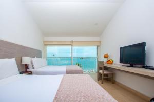 a hotel room with a bed and a television at Tamaca Beach Resort in Santa Marta