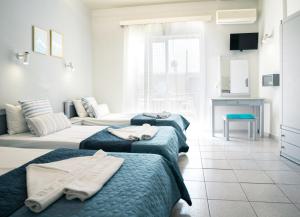 アムーダラ・イラクリオンにあるRODI BLUE appartmentsのベッドルーム1室(ベッド3台付)、リビングルーム1室
