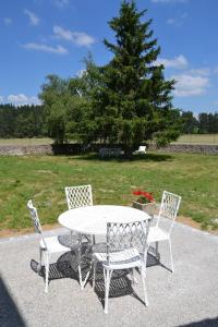 a white table and chairs with a tree in the background at Gîte de Romagers in La Chaze-de-Peyre