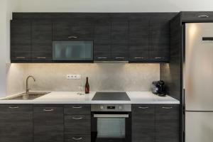 a kitchen with black cabinets and a sink and a refrigerator at Kamares Boutique Residence in Rethymno Town