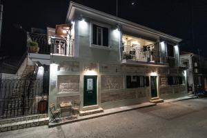 a white building with green doors and balconies at night at Antheon apartments in Vathi, Ithaka