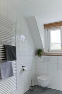 a white bathroom with a toilet and a window at Haus Nagel in Hinterzarten