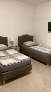 two twin beds in a room with a lamp at Hostel Ellwürder Hof in Nordenham