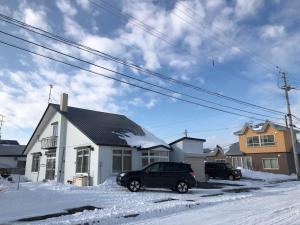 une voiture garée devant une maison dans la neige dans l'établissement Guest House Hagoromo 39 - Vacation STAY 12003v, à Kiyosato
