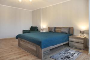 a bedroom with a large bed and a chair at Apartamenty NA PODDASZU in Chełmża