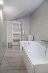 NA PODDASZU في كومزا: حمام أبيض مع حوض استحمام ودش
