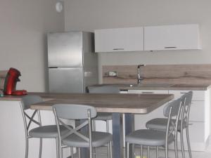 Una cocina con una mesa con sillas y un refrigerador. en Gîte de Romagers, en La Chaze-de-Peyre