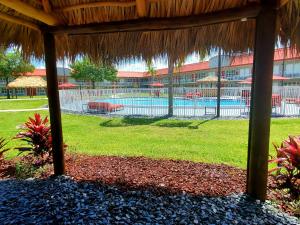 un complejo con piscina y sombrilla de paja en Vero Beach Inn & Suites Vero Beach I-95, en Vero Beach