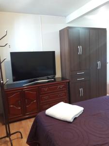 1 dormitorio con TV de pantalla plana y vestidor en Hospedaje Kelita en Moquegua