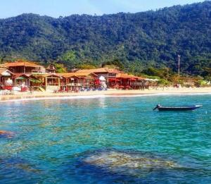 Trindade Hospeda -Casa 1- Você a Varanda e o Mar في ترينيداد: قارب في الماء بجانب شاطئ