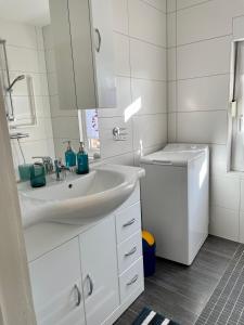 een witte badkamer met een wastafel en een wasmachine bij Thea 