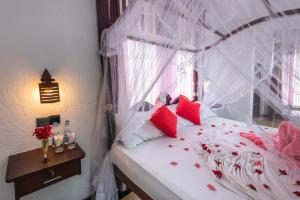 een slaapkamer met een wit bed met rode kussens bij Seaview Deepal villa in Unawatuna