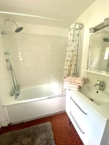 Baño blanco con bañera y lavamanos en Cottage au sein du "Hameau du golf" de la Bretesche, en Missillac