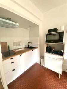 een keuken met witte kasten en een magnetron bij Cottage au sein du "Hameau du golf" de la Bretesche in Missillac