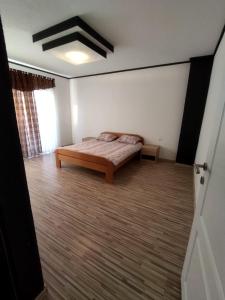 - une chambre avec un lit et du parquet dans l'établissement Apartmani Posušje, à Posušje